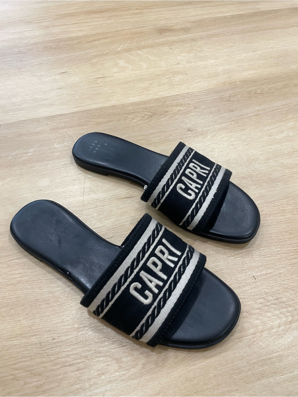 A New Day black slides with white stripes and 'CAPRI' text size 8